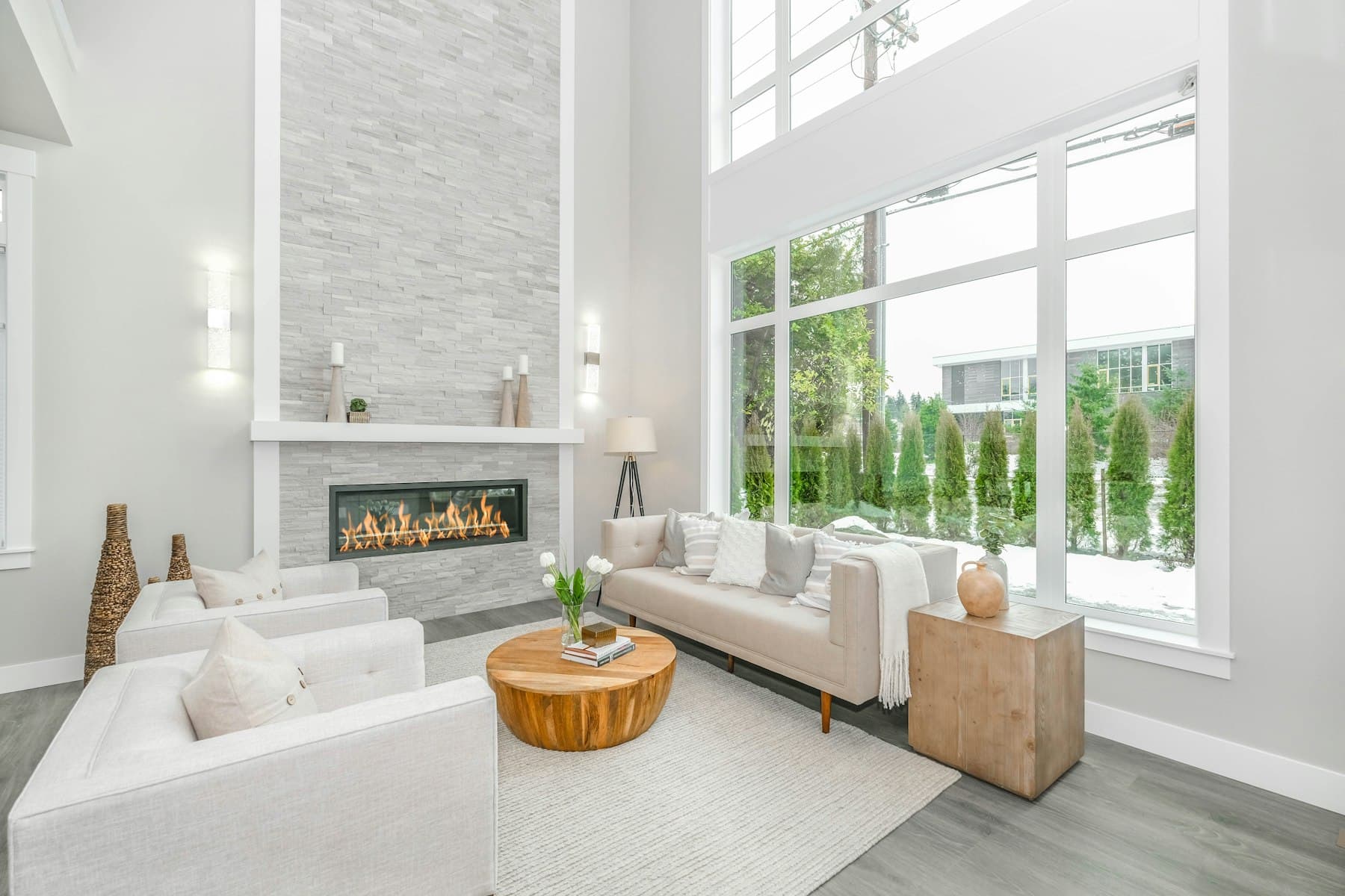 Salon lumineux et rangé, canapé clair devant une baie vitrée
